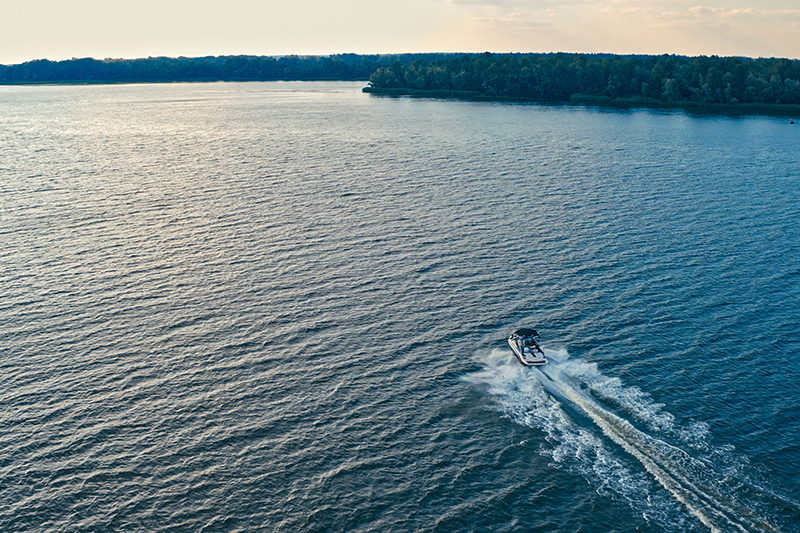 powerboat-on-lake Speedboat cruising across a wide lake at sunset with a forested shoreline in the background.